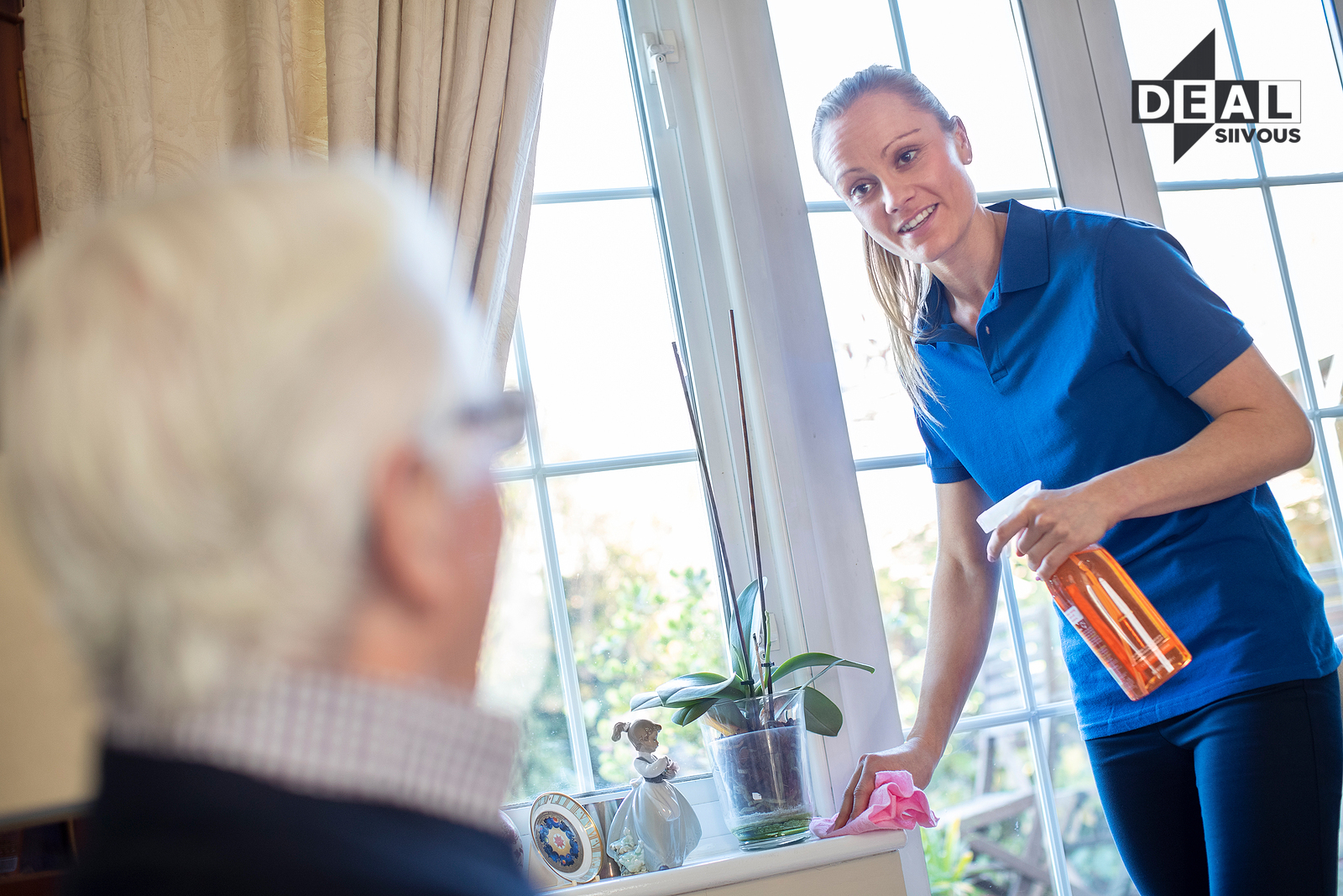 Ystävällinen siivoustyöntekijä auttaa ikäihmistä kotisiivouksessa Deal Siivouksen palveluna.